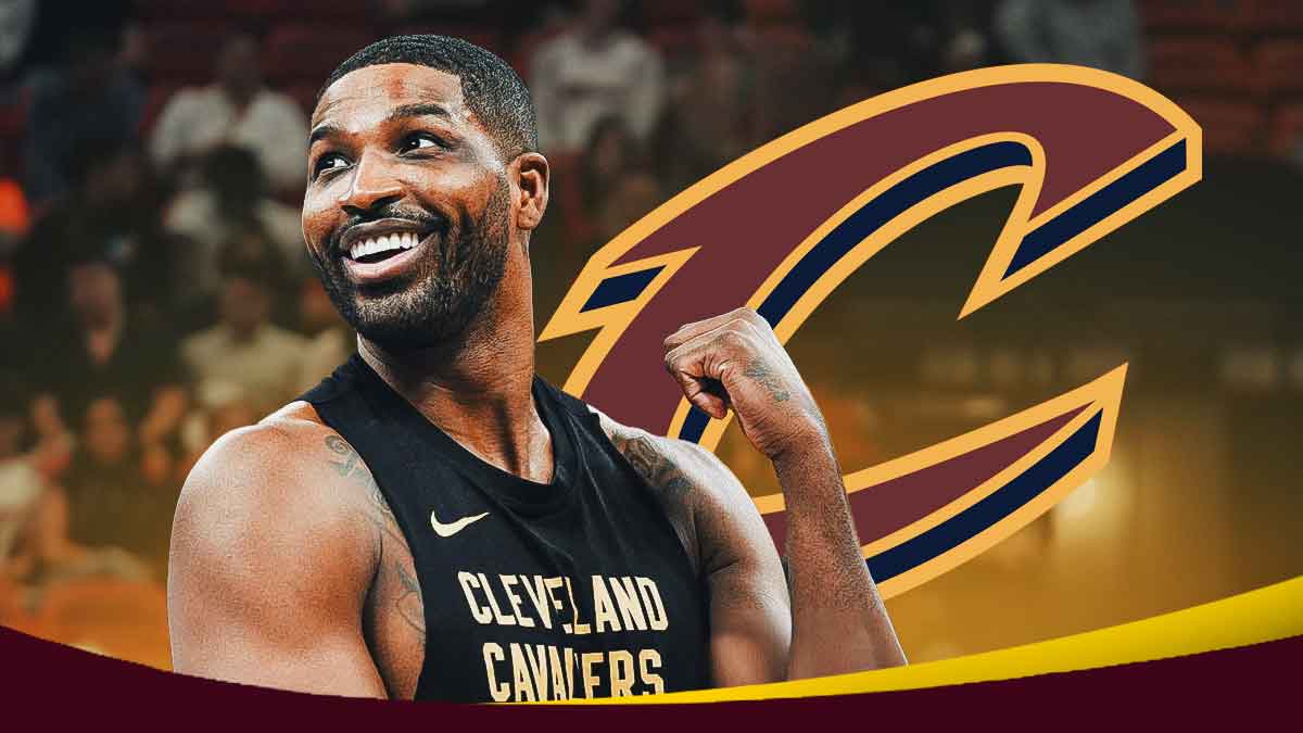 Cavs center Tristan Thompson smiling next to the Cavs logo standing outside of Rocket Mortgage FieldHouse