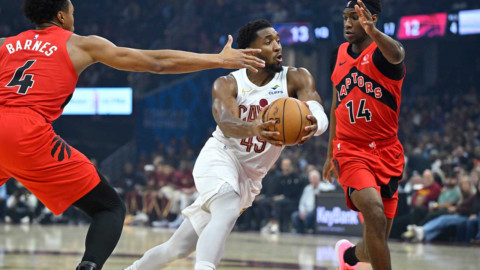 Cleveland Cavaliers guard Donovan Mitchell (45) drives between Toronto Raptors forward Scottie Barnes (4) and guard Ja'Kobe Walter (14) in the first quarter at Rocket Arena.