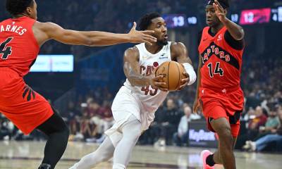 Cleveland Cavaliers guard Donovan Mitchell (45) drives between Toronto Raptors forward Scottie Barnes (4) and guard Ja'Kobe Walter (14) in the first quarter at Rocket Arena.