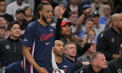 Clippers guard Darius Garland (10) reacts on the bench after a basket in the first half against the Golden State Warriors during the play-in rounds of the 2026 NBA Playoffs at Intuit Dome with the Cavs logo in the background